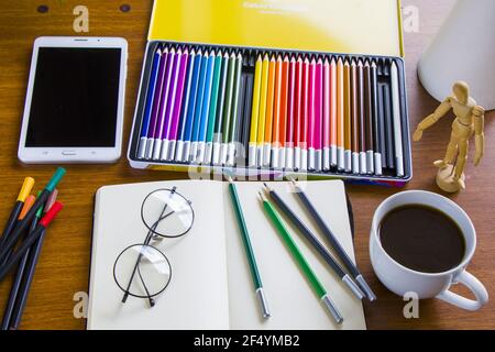 Schreibtisch mit Skizzenstiften und Skizzenbuch, leerem Papier und bunten Bleistiften Stockfoto