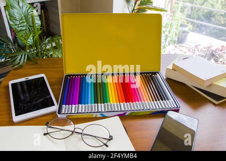 Schreibtisch mit Skizzenstiften und Skizzenbuch, leerem Papier und bunten Bleistiften Stockfoto