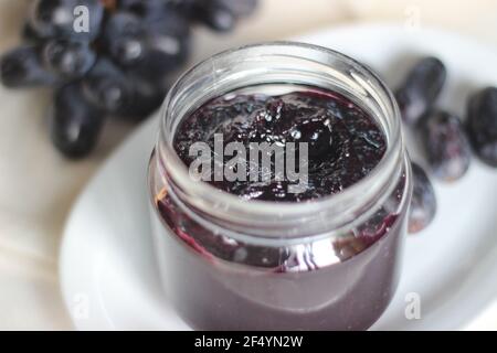 Hausgemachte Traubenmarmelade mit drei Zutaten, kernlosen schwarzen Trauben, Zucker und Limettensaft. Aufnahme auf weißem Hintergrund Stockfoto