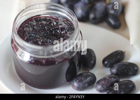 Hausgemachte Traubenmarmelade mit drei Zutaten, kernlosen schwarzen Trauben, Zucker und Limettensaft. Aufnahme auf weißem Hintergrund Stockfoto