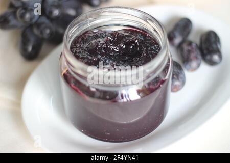 Hausgemachte Traubenmarmelade mit drei Zutaten, kernlosen schwarzen Trauben, Zucker und Limettensaft. Aufnahme auf weißem Hintergrund Stockfoto