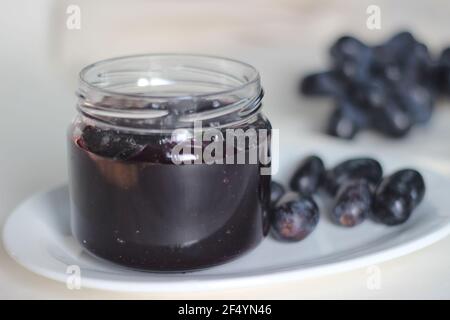 Hausgemachte Traubenmarmelade mit drei Zutaten, kernlosen schwarzen Trauben, Zucker und Limettensaft. Aufnahme auf weißem Hintergrund Stockfoto