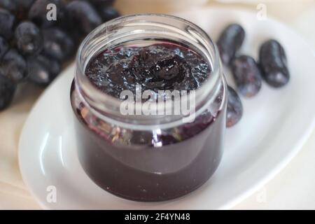 Hausgemachte Traubenmarmelade mit drei Zutaten, kernlosen schwarzen Trauben, Zucker und Limettensaft. Aufnahme auf weißem Hintergrund Stockfoto