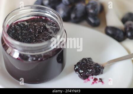 Hausgemachte Traubenmarmelade mit drei Zutaten, kernlosen schwarzen Trauben, Zucker und Limettensaft. Aufnahme auf weißem Hintergrund Stockfoto