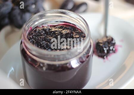 Hausgemachte Traubenmarmelade mit drei Zutaten, kernlosen schwarzen Trauben, Zucker und Limettensaft. Aufnahme auf weißem Hintergrund Stockfoto