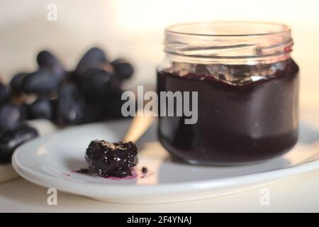 Hausgemachte Traubenmarmelade mit drei Zutaten, kernlosen schwarzen Trauben, Zucker und Limettensaft. Aufnahme auf weißem Hintergrund Stockfoto