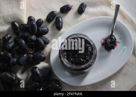 Hausgemachte Traubenmarmelade mit drei Zutaten, kernlosen schwarzen Trauben, Zucker und Limettensaft. Aufnahme auf weißem Hintergrund Stockfoto