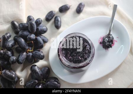 Hausgemachte Traubenmarmelade mit drei Zutaten, kernlosen schwarzen Trauben, Zucker und Limettensaft. Aufnahme auf weißem Hintergrund Stockfoto