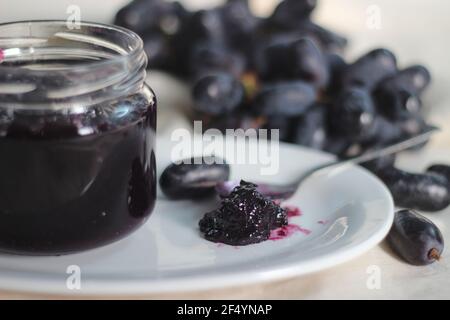 Hausgemachte Traubenmarmelade mit drei Zutaten, kernlosen schwarzen Trauben, Zucker und Limettensaft. Aufnahme auf weißem Hintergrund Stockfoto