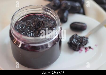 Hausgemachte Traubenmarmelade mit drei Zutaten, kernlosen schwarzen Trauben, Zucker und Limettensaft. Aufnahme auf weißem Hintergrund Stockfoto