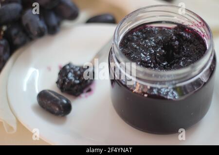 Hausgemachte Traubenmarmelade mit drei Zutaten, kernlosen schwarzen Trauben, Zucker und Limettensaft. Aufnahme auf weißem Hintergrund Stockfoto