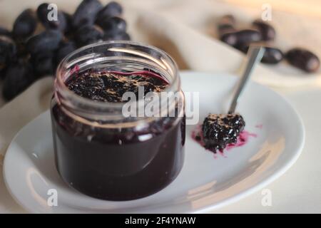 Hausgemachte Traubenmarmelade mit drei Zutaten, kernlosen schwarzen Trauben, Zucker und Limettensaft. Aufnahme auf weißem Hintergrund Stockfoto