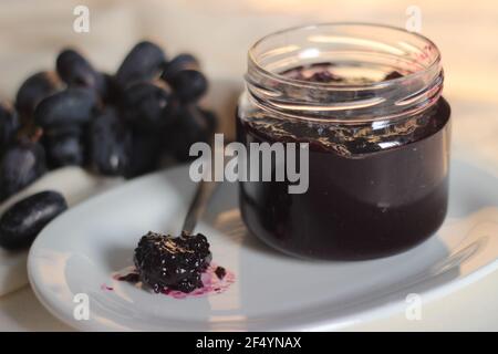 Hausgemachte Traubenmarmelade mit drei Zutaten, kernlosen schwarzen Trauben, Zucker und Limettensaft. Aufnahme auf weißem Hintergrund Stockfoto