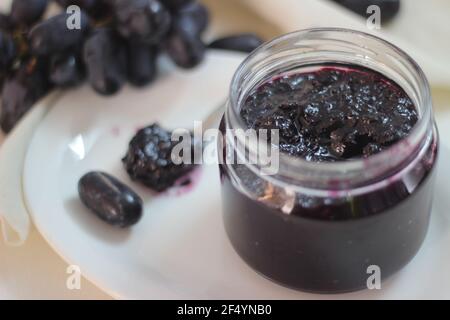 Hausgemachte Traubenmarmelade mit drei Zutaten, kernlosen schwarzen Trauben, Zucker und Limettensaft. Aufnahme auf weißem Hintergrund Stockfoto