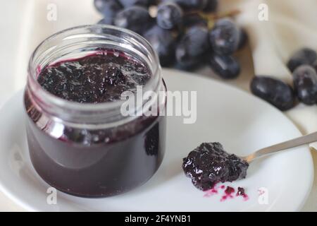 Hausgemachte Traubenmarmelade mit drei Zutaten, kernlosen schwarzen Trauben, Zucker und Limettensaft. Aufnahme auf weißem Hintergrund Stockfoto