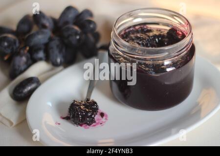 Hausgemachte Traubenmarmelade mit drei Zutaten, kernlosen schwarzen Trauben, Zucker und Limettensaft. Aufnahme auf weißem Hintergrund Stockfoto