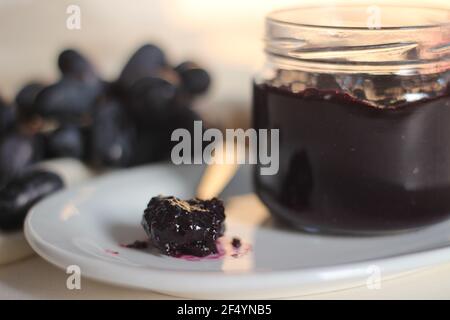 Hausgemachte Traubenmarmelade mit drei Zutaten, kernlosen schwarzen Trauben, Zucker und Limettensaft. Aufnahme auf weißem Hintergrund Stockfoto