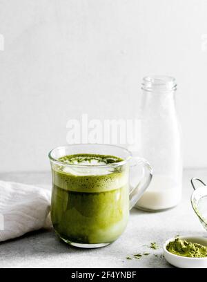 Frühstücksszene: Frisch zubereiteter veganer Matcha Maca Latte, der als Getränk nach dem Frühstück serviert wird. Stockfoto