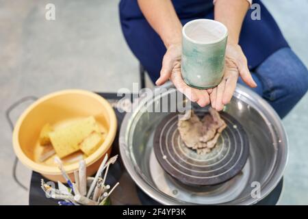 Nahaufnahme der Hände einer Frau, die handgefertigten Ton hält Keramikprodukt während der Arbeit in Töpferei Stockfoto