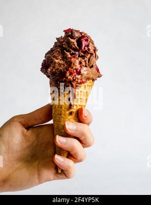Hand hält schmelzende, hausgemachte, nicht-Churn vegane Süßkartoffel Schokolade Eis mit Schokolade Chips und gehackte Kirschen. Perfekter Sommergenuss. Stockfoto