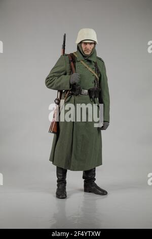 Männlicher Schauspieler in der Winteruniform eines deutschen Soldaten, der Periode 1942, dem Zweiten Weltkrieg, posiert auf grauem Hintergrund Stockfoto