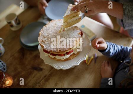 Mutter schneiden und servieren hausgemachten Erdbeerkuchen Stockfoto