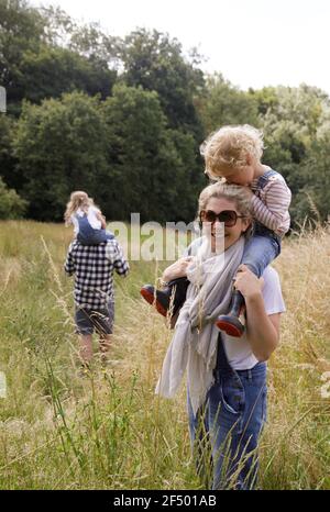 Porträt glückliche Mutter trägt Tochter auf Schultern in ländlichen Feld Stockfoto