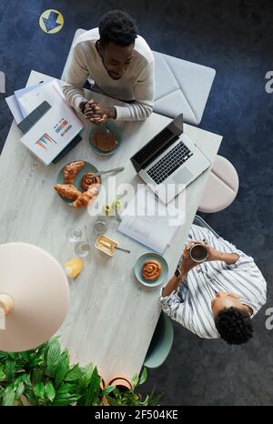 Geschäftsleute, die beim Frühstück am Bürotisch sprachen Stockfoto