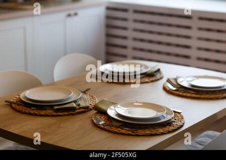 Weiße Platten mit Edelstahl Löffel und Gabeln auf der Platte Matten auf Holztisch. Stockfoto