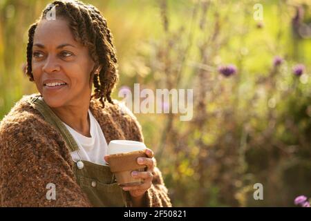 Lächelnde Frau, die Kaffee im sonnigen Garten genießt Stockfoto