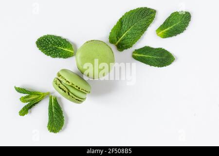 Minze Makronen Dessert auf weißem Hintergrund Draufsicht. Französische Meringue-Keksmakarons mit Minzblättern. Stockfoto