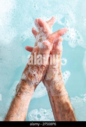 Nahaufnahme einer älteren Frau, die sich in Seifenwasser die Hände wäscht Stockfoto