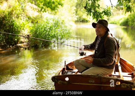 Mann Fliegenfischen von Ruderboot auf sonnigen Fluss Stockfoto