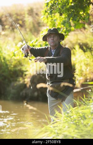 Mann Gießen Fliegenfischen Stange am sonnigen Fluss Stockfoto