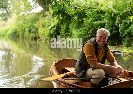 Portrait glücklicher Mann Fliegenfischen im Boot auf dem Fluss Stockfoto