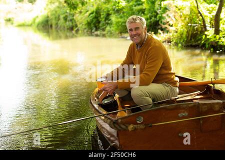 Portrait glücklicher Mann mit Kaffee Fliegenfischen im Boot auf Fluss Stockfoto