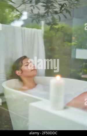 Heitere Frau genießen Schaumbad im Badezimmer Stockfoto