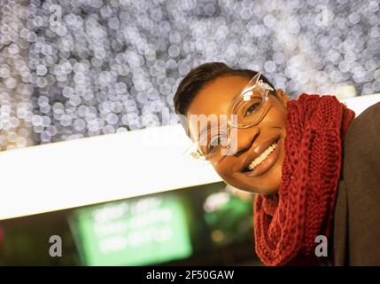 Portrait glückliche junge Frau in funky Brille und Schal unten Leuchtet Stockfoto