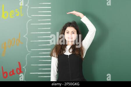 Vorpubertär Mädchen Messung ihrer Höhe auf gezeichneten Kreide Höhe Meter. Mädchen ist hinter der Schule Board Hintergrund. Hochauflösendes Foto. Volle Tiefe von Stockfoto