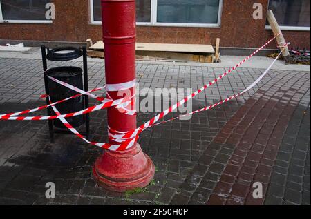 Rot-weiß gestreiftes Plastikband schränkt den Zugang zur Baustelle ein. Stockfoto