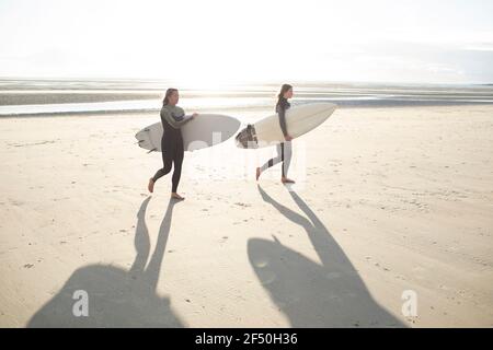 Junge Surferinnen mit Surfbrettern am sonnigen Sommerstrand Stockfoto