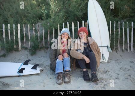 Portrait glückliche junge Surferinnen mit Surfbrettern am Strandweg Stockfoto