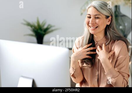Selbstbewusste, erfolgreiche, schöne asiatische Frau, Managerin oder geschäftsführerin, die von zu Hause aus arbeitet, per Videokonferenz mit Mitarbeitern oder Freunden chattet, online trifft, mit den Händen gestikelt und freundlich lächelt