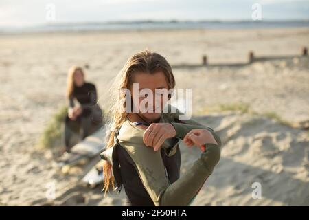 Junge Surferin, die im sonnigen Sommer nasse Anzugsommer anlegt Strand Stockfoto