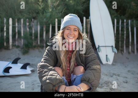 Portrait glücklich schöne junge Surferin am Strand sitzen Stockfoto