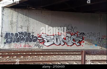 Street Graffiti Kunstwerk auf einer Wand in einem Eisenbahntunnel mit Bahngleisen vorne mit Buchstaben und Wörtern in fetter Schrift, Krakau, Polen Stockfoto