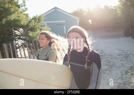 Portrait glückliche junge Surferin mit Surfbrett am sonnigen Strand Pfad Stockfoto