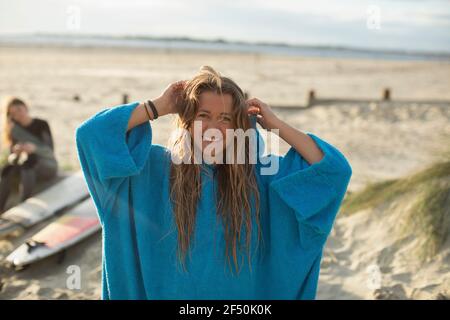 Portrait glücklich junge Surferin mit nassem Haar auf sonnigen Strand Stockfoto
