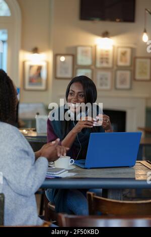 Glückliche Geschäftsfrauen reden und arbeiten am Laptop im Café Stockfoto