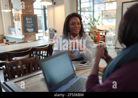 Geschäftsfrauen treffen sich und reden am Laptop im Café Stockfoto